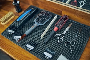Foto de personas de diferentes herramientas de peluquería colocadas sobre una superficie limpia en una barbería