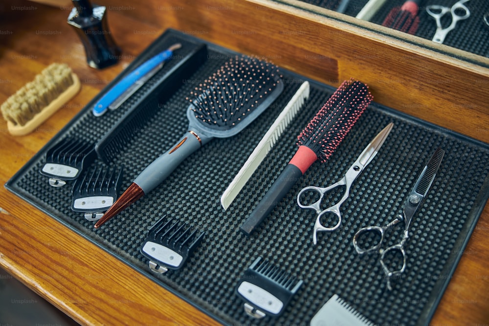 Foto de personas de diferentes herramientas de peluquería colocadas sobre una superficie limpia en una barbería