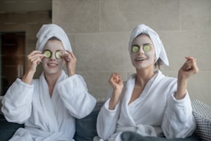 Eye mask. Young women with towel on heads having cucumber eye mask