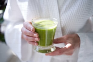 Close up of lady wearing white bathrobe and holding healthy drink
