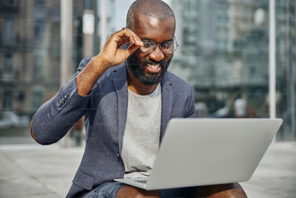 Cheerful male person keeping smile on his face while having pleasant conversation