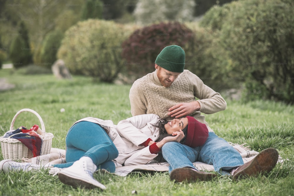 Bon week-end. Un jeune couple se détend sur l’herbe pendant le pique-