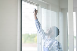 Jeune réparateur africain en salopette installant une fenêtre