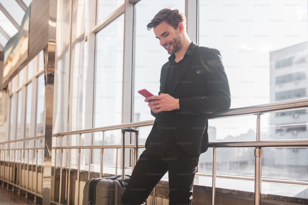 Internet gratis. Un hombre enviando mensajes de texto con sus amigos en el aeropuerto