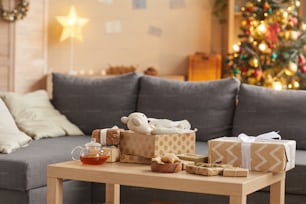 Background image of cozy home interior with Christmas gifts on table in foreground, copy space