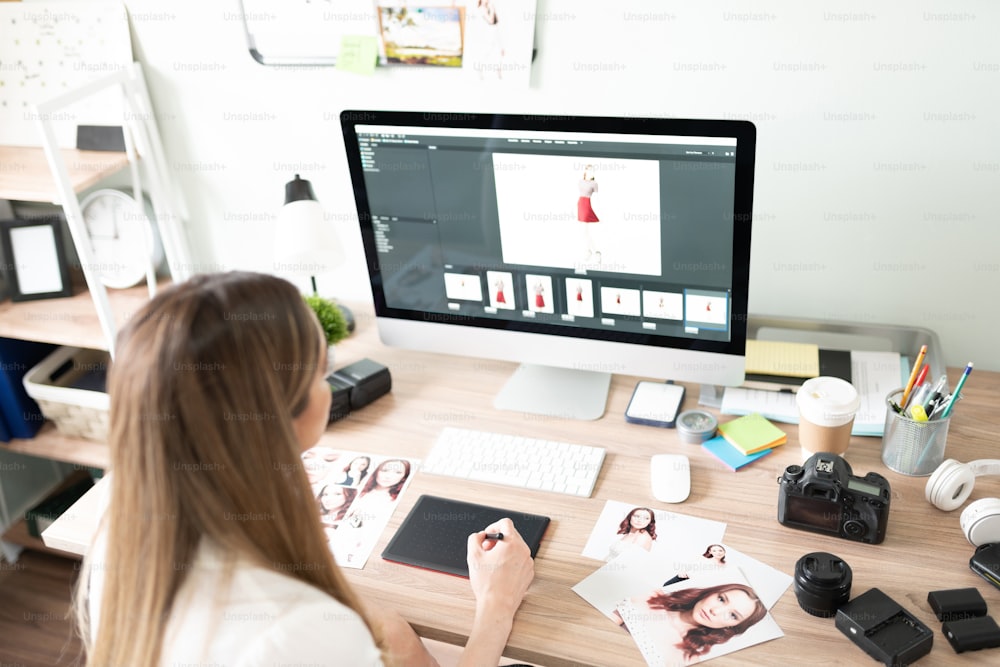 Rear view of a female photographer culling and developing some of her photos from a recent shoot in a computer