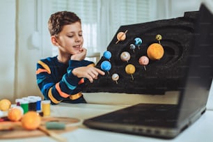 Kid apresentando seu projeto de casa de ciência - os planetas do nosso sistema solar. Educação a distância online.