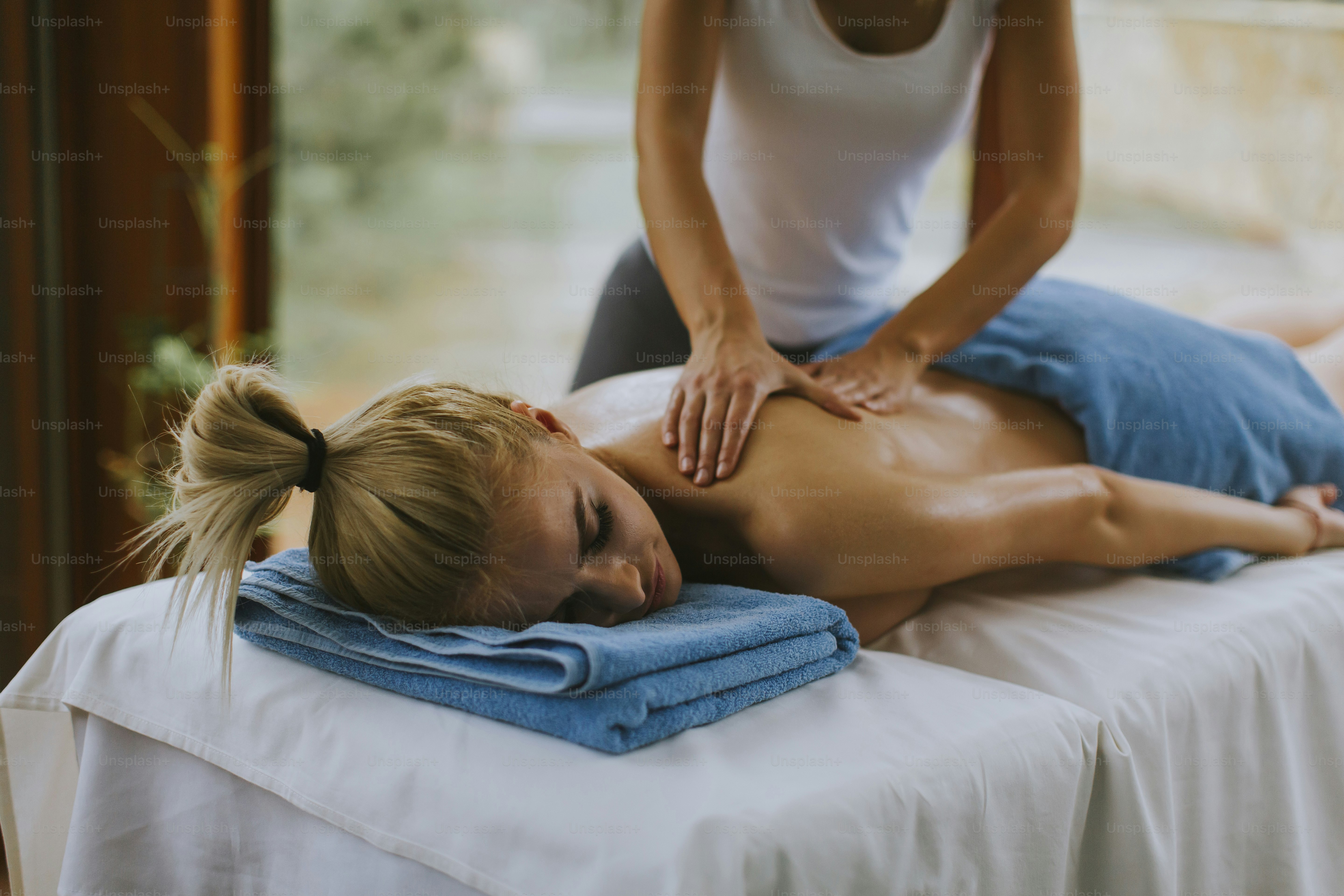 Schöne junge Frau liegt und hat Rückenmassage im Spa-Salon während der Wintersaison