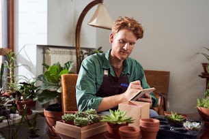 Portrait of red head florist writing notes in notebook in flower shop