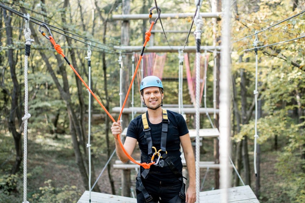 Portrait of a happy well-equipped climbing instructor in a rope park outdoors