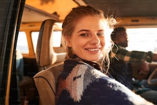 Peaceful female traveler is breathing fresh air at the forest with enjoyment. She is looking to the window with relaxation while driving at the car