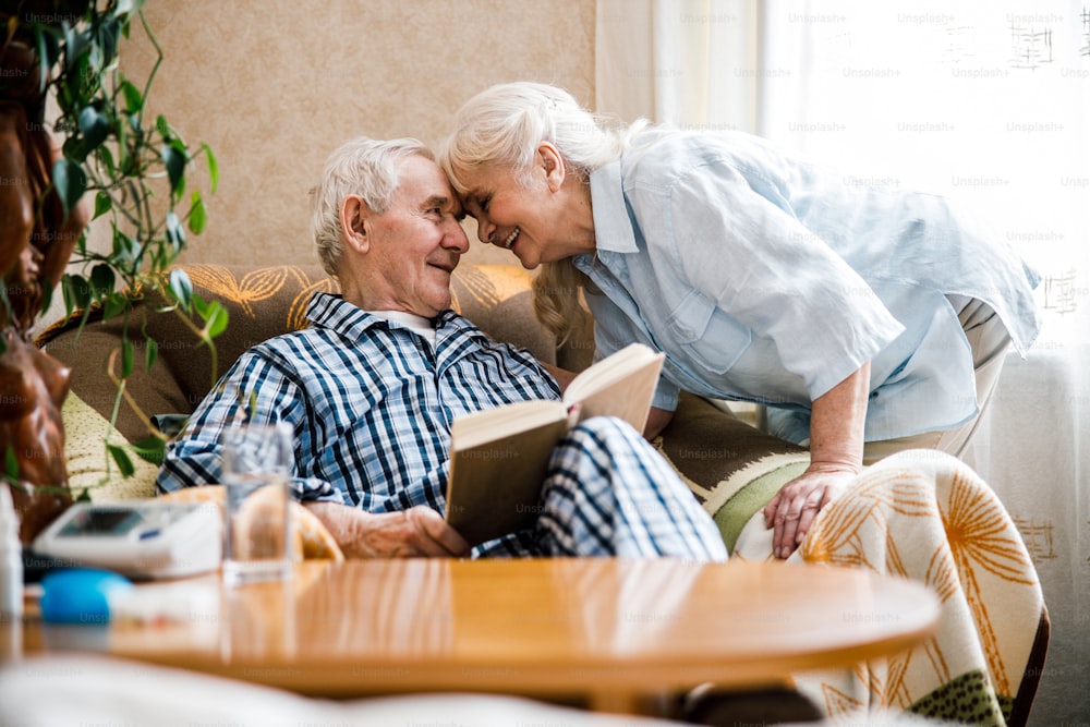 居間で抱き合い、頭を優しく押し付け合う年配の中年の幸せな夫婦。ストックフォト