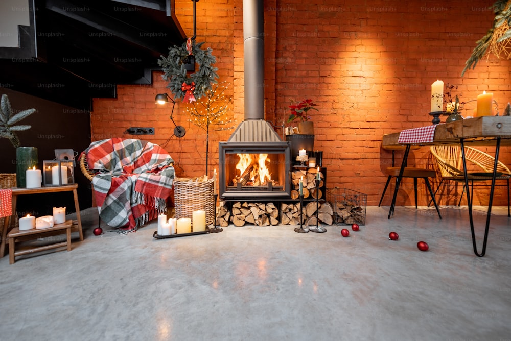 Área de chimenea de un hermoso interior estilo loft con pisos de ladrillo real y concreto decorados para las vacaciones de Año Nuevo. El concepto de confort en el hogar