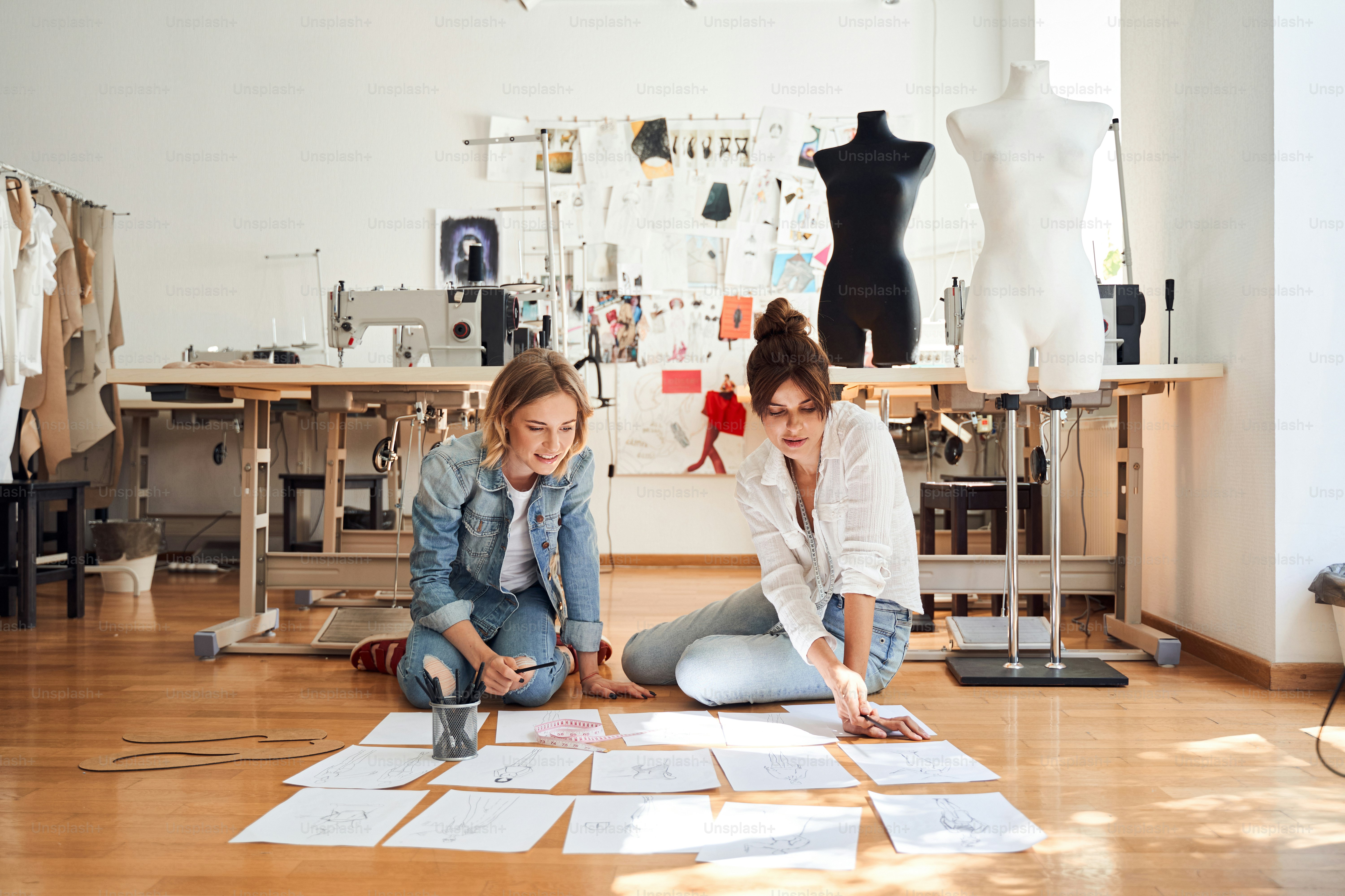 Creative designer and her assistant are sitting on the floor and ...