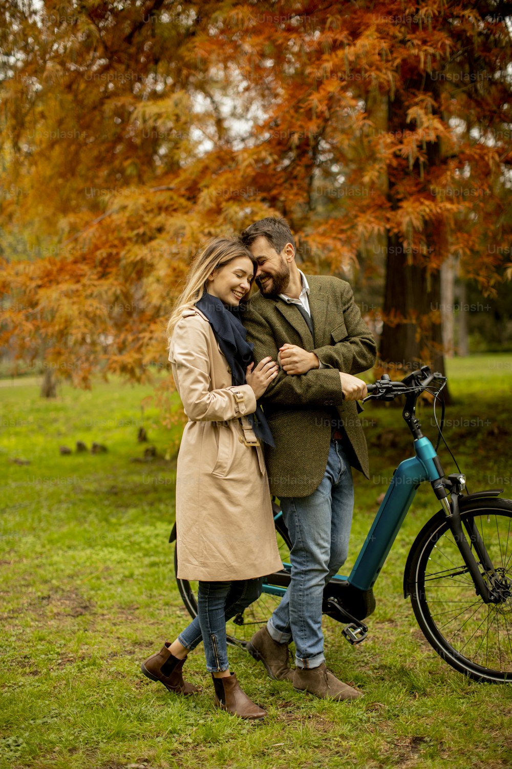 Handsome young couple in the autumn park with electrical bicycle