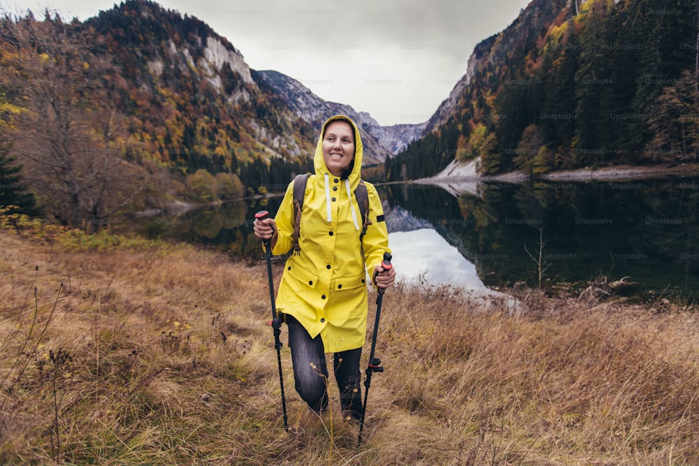 Woman with backpack and raincoat hiking Lifestyle adventure concept forest and lake on background active vacations into the wild