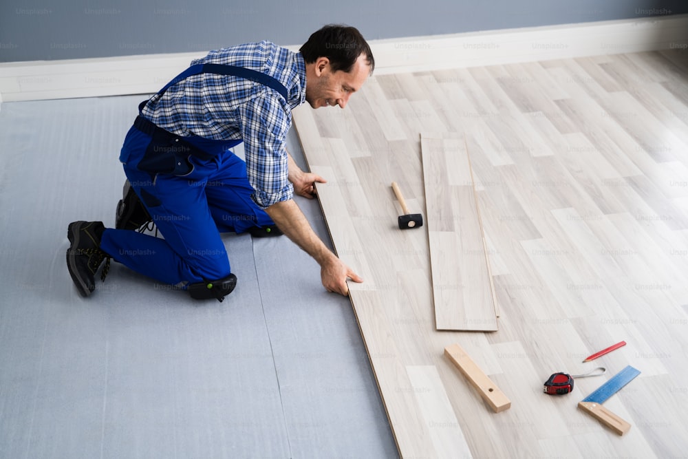 Hardwood Floor Renovation. Construction Worker Doing New Laminate Installation