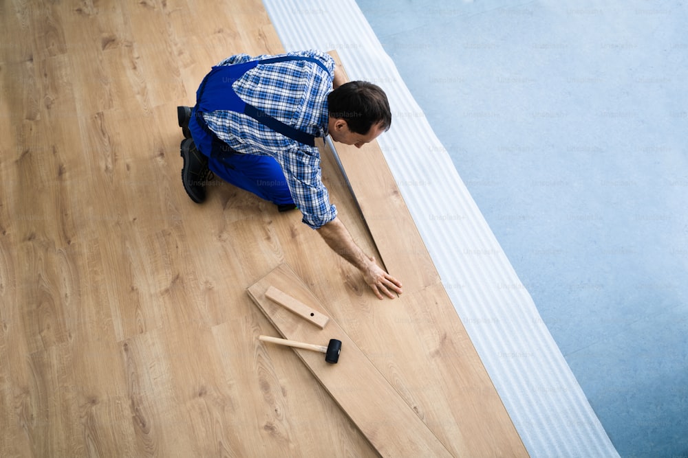 Hardwood Floor Renovation. Construction Worker Doing New Laminate Installation