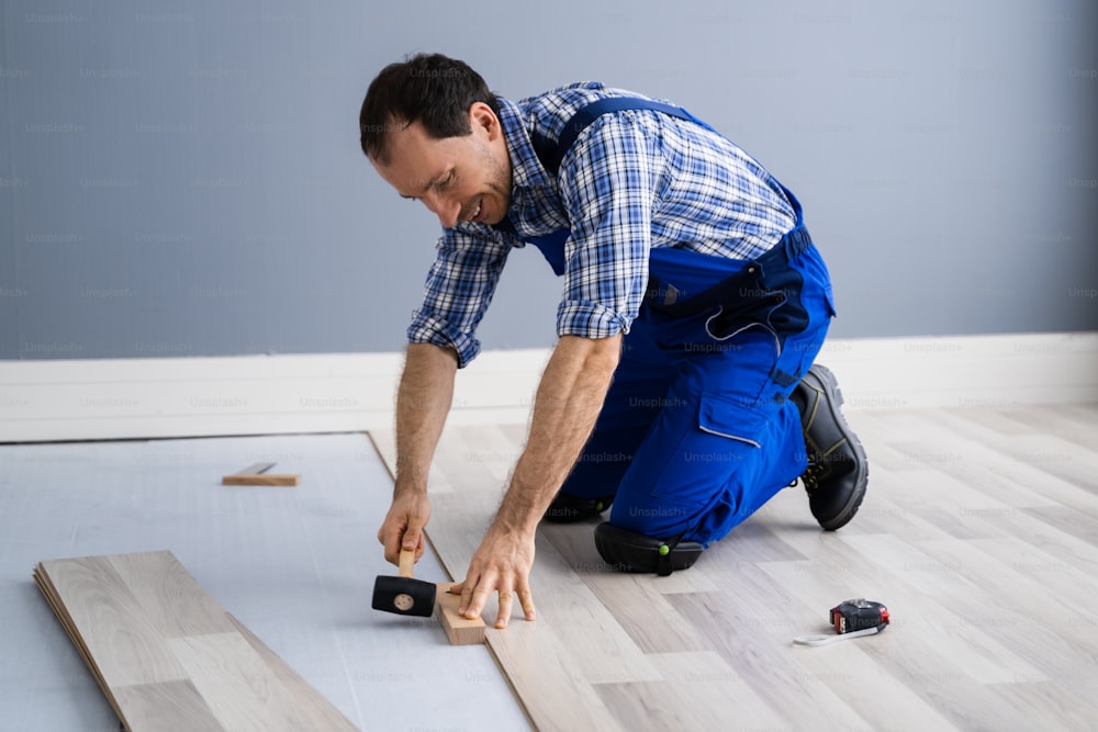 Hardwood Floor Renovation. Construction Worker Doing New Laminate Installation