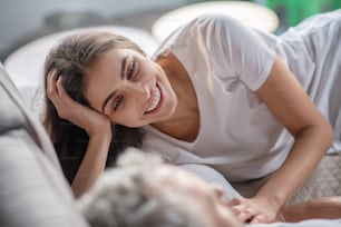 Just woke up. A woman talking to a man while staying in the bed