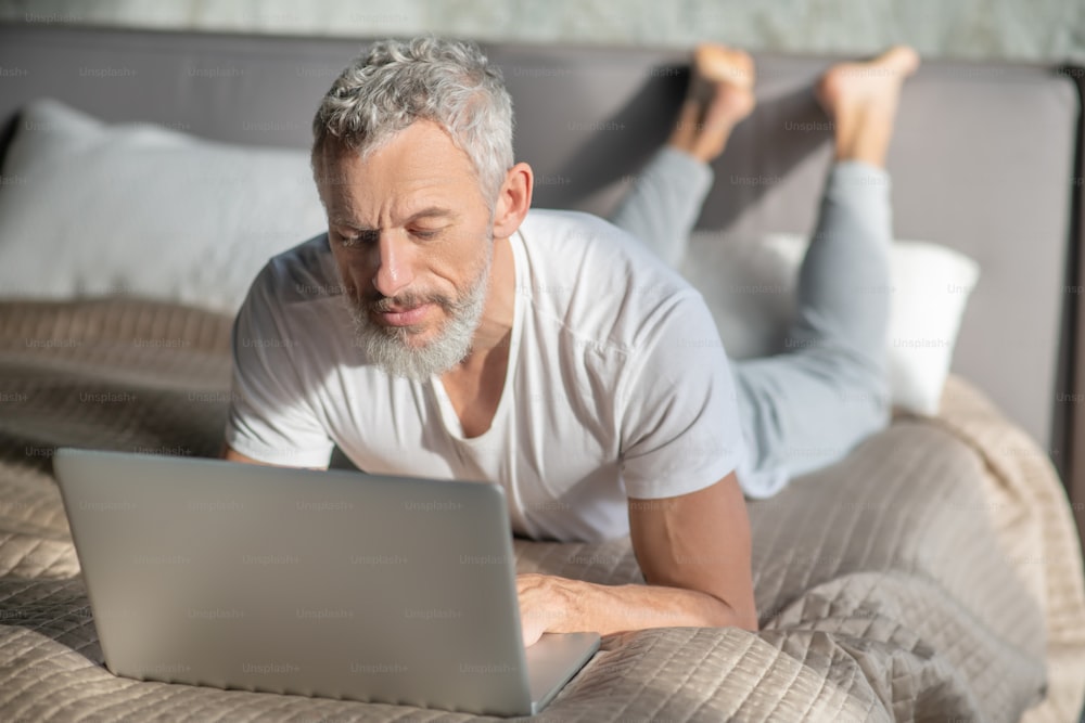 Freelancer. A grey-haired man using a computer while staying at home