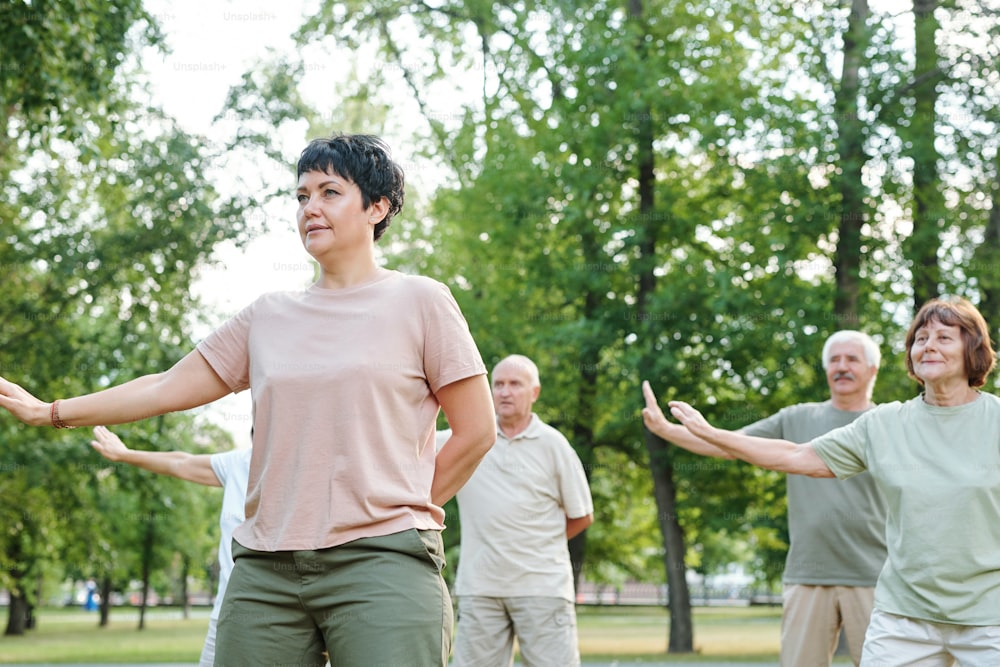 Mature woman training outdoors in the park with other mature people in the background