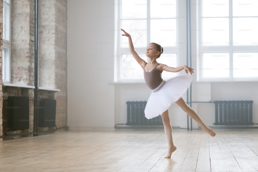 Piccola ballerina in bellissimo vestito tutù che impara la danza classica nello studio di danza