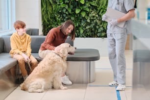 수의사에게 보여주기 위해 개와 함께 수의사 진료소에 오는 가족