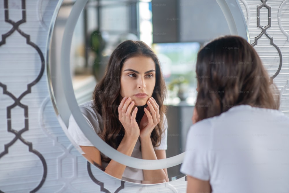 Beauty. A woman looking at her reflection in the mirror