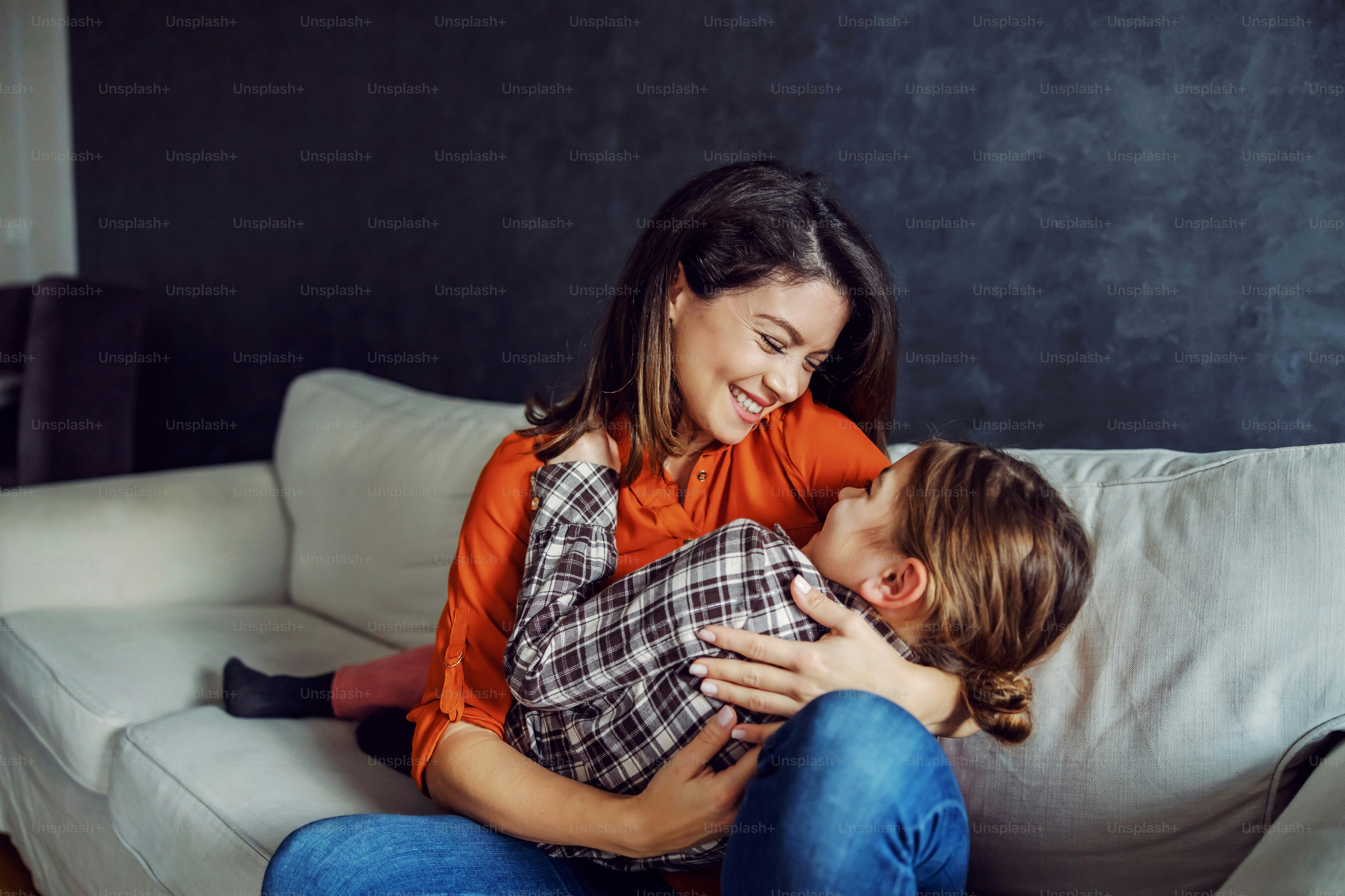 Happy mother holding her daughter in her hands and hugging her. Playtime for happy family.