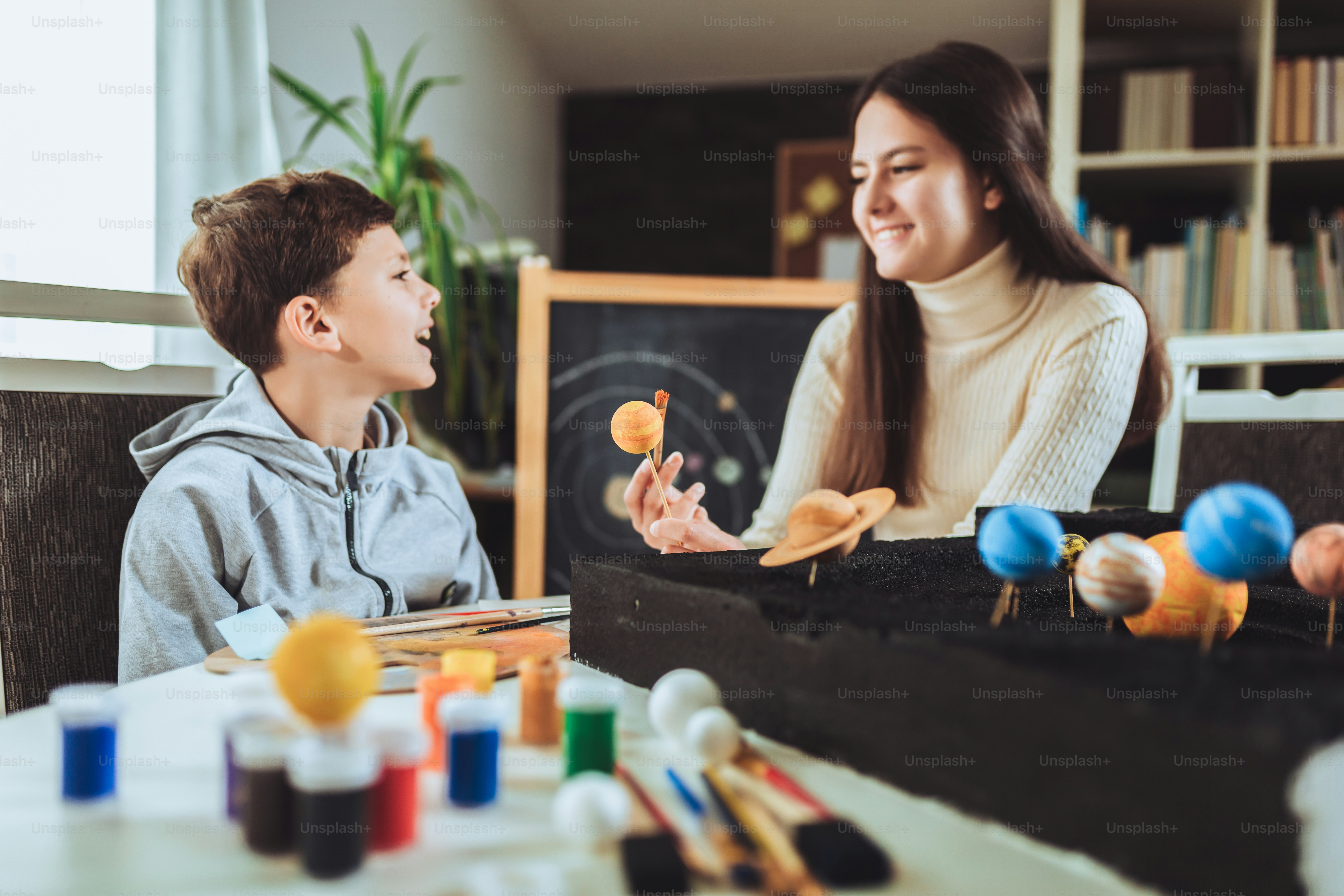 Happy school boy and girl  making a solar system for a school science project at home