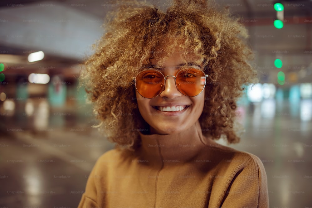 Retrato de una sonriente chica de hip hop de raza mixta con gafas de sol mirando a la cámara.