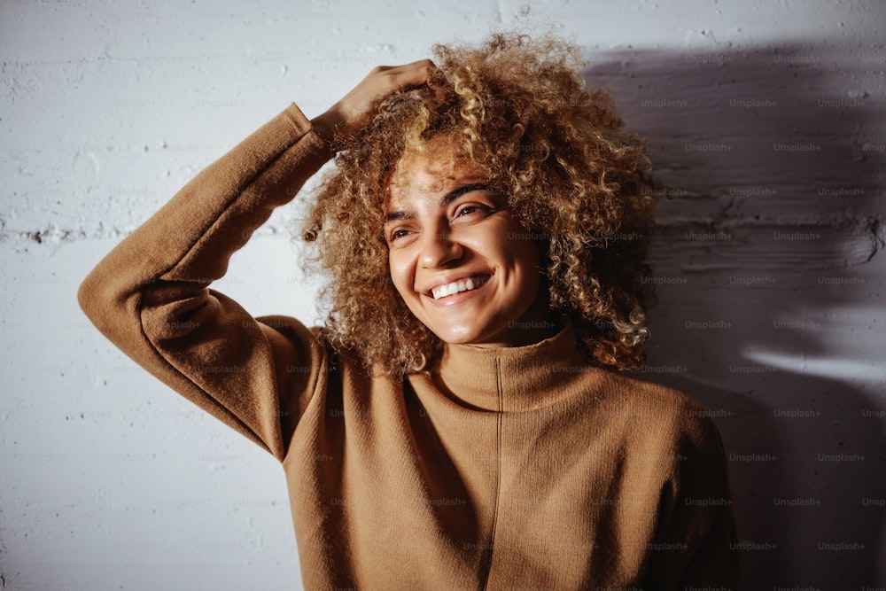 Portrait of smiling mixed race trap girl. Girl is standing against the wall.