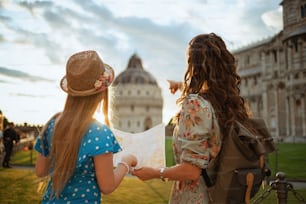 Visto desde detrás de una elegante madre e hijo con mapa y mochila cerca de la Catedral de Pisa.