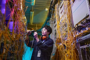Ritratto in vita del giovane tecnico di rete che collega i cavi nella sala server, spazio di copia