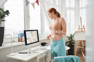 Skilful doctor wearing uniform headset giving consultation to client via internet. Woman consulting online with doctor using virtual webcam conference on computer. Distant communication and protection concept