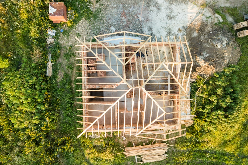 Aerial view of unfinished brick house with wooden roof structure under construction.