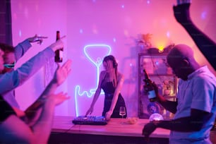 Pretty girl with long blond hair standing by counter with turntables while mixing music for disco dancing and enjoying at home party with friends