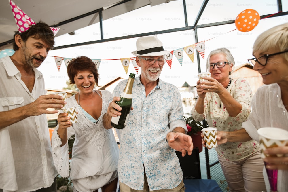 Persone anziane che festeggiano il compleanno nel cottage sul fiume divertendosi.