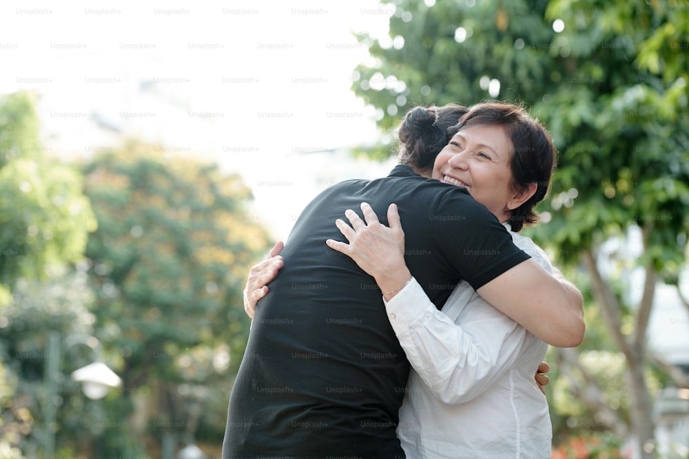Cheerful mature woman happy to see her adult son after quarantine is over, she is smiling and hugging him
