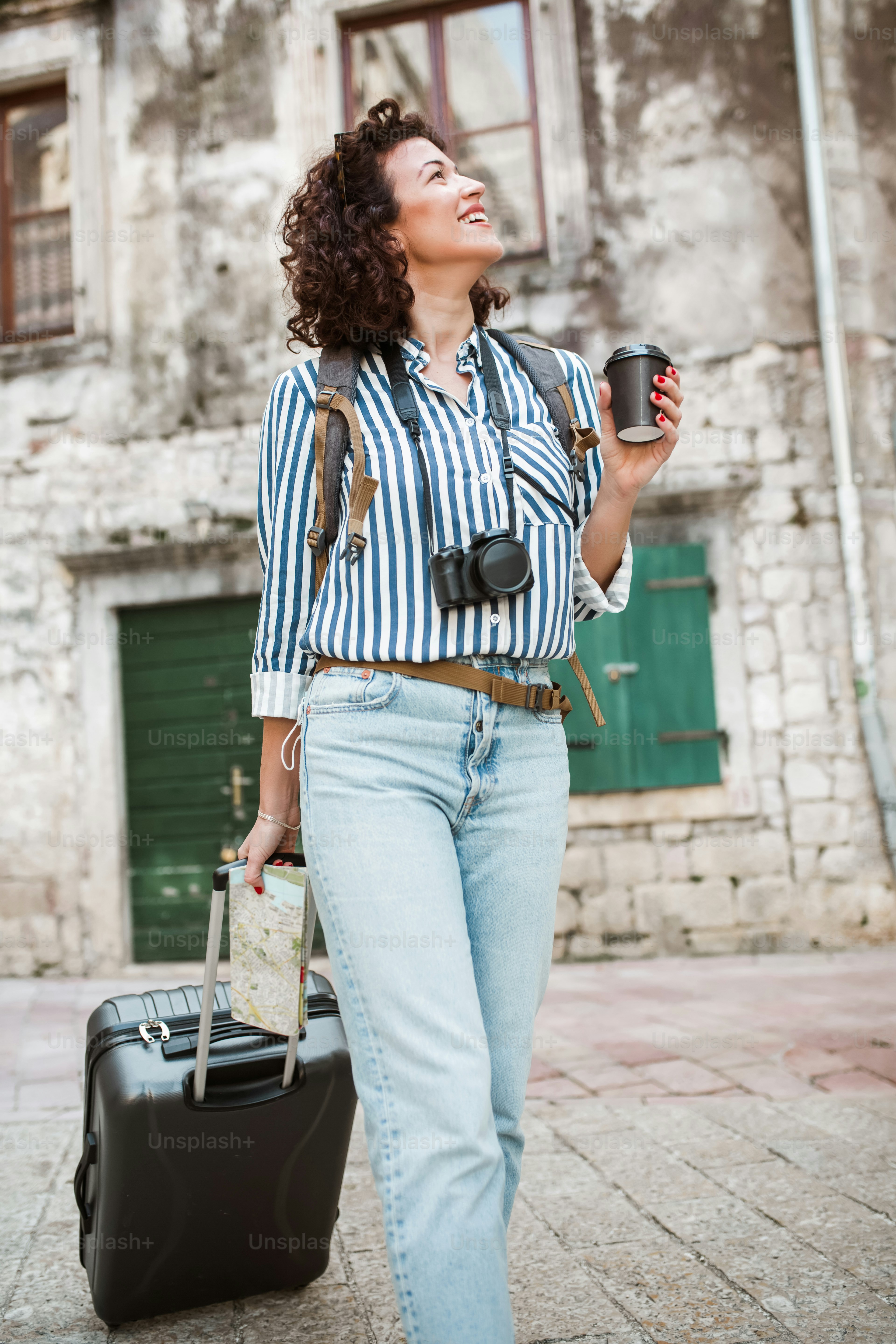 Mujer turista caminando con maleta en la calle en la ciudad vieja europea.