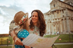 smiling modern mother and daughter with map having walking tour near Pisa Cathedral.