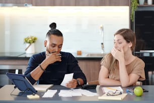 Young mixed-race couple covering mouth as they are shocked with sum in unpaid bill