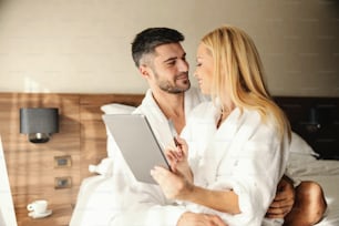 Weekends for relaxation, online spa reservations from a hotel room. The handsome guy is having his lover in his lap and gently hugging her Online payment Online dinner and spa reservation Credit card