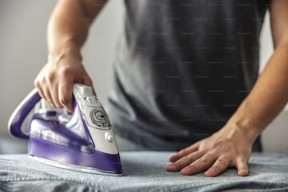 A man at work, doing housework. Make it easy to use the hand iron by lightly pressing the laundry iron on the crumpled shirt. The concept of a modern open minded married life