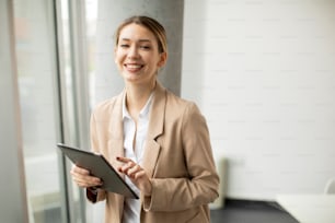 Mulher jovem bonita segurando tablet digital no escritório moderno