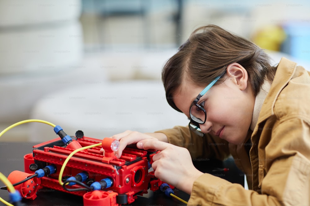 Seitenansichtsporträt eines niedlichen Jungen, der eine Robotermaschine baut, während er den Ingenieurunterricht in der Entwicklungsschule genießt