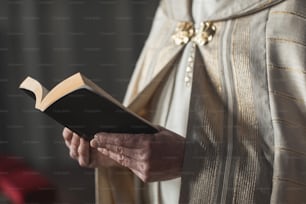 Nahaufnahme eines Priesters, der während der Zeremonie in der Kirche die Bibel hält und Gebete liest