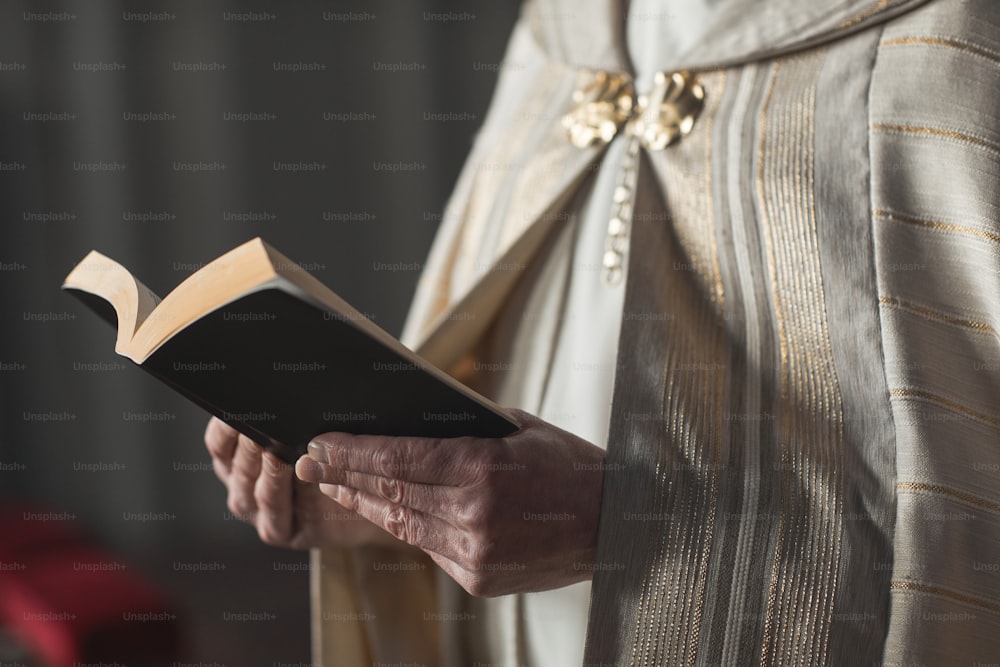 Close-up do padre segurando a Bíblia e lendo orações durante cerimônia na igreja