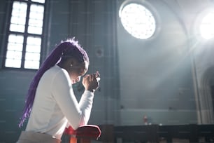 Giovane donna africana seduta davanti all'altare in chiesa e pregante